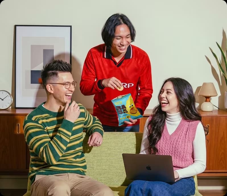 Tiga rekan kerja tertawa sambil ngemil RASA di kantor