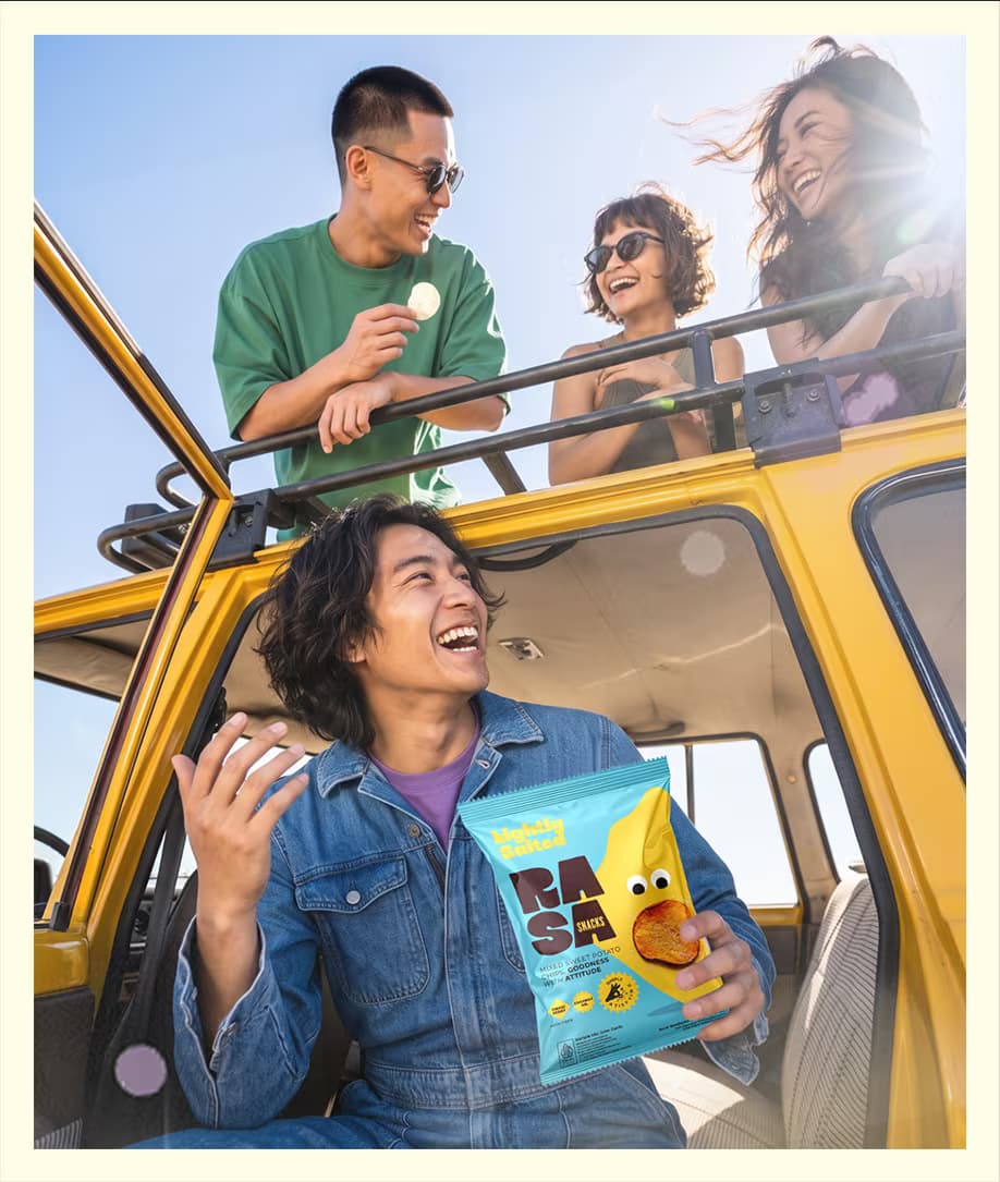 Tiga teman tertawa di atas mobil kuning sambil memegang RASA